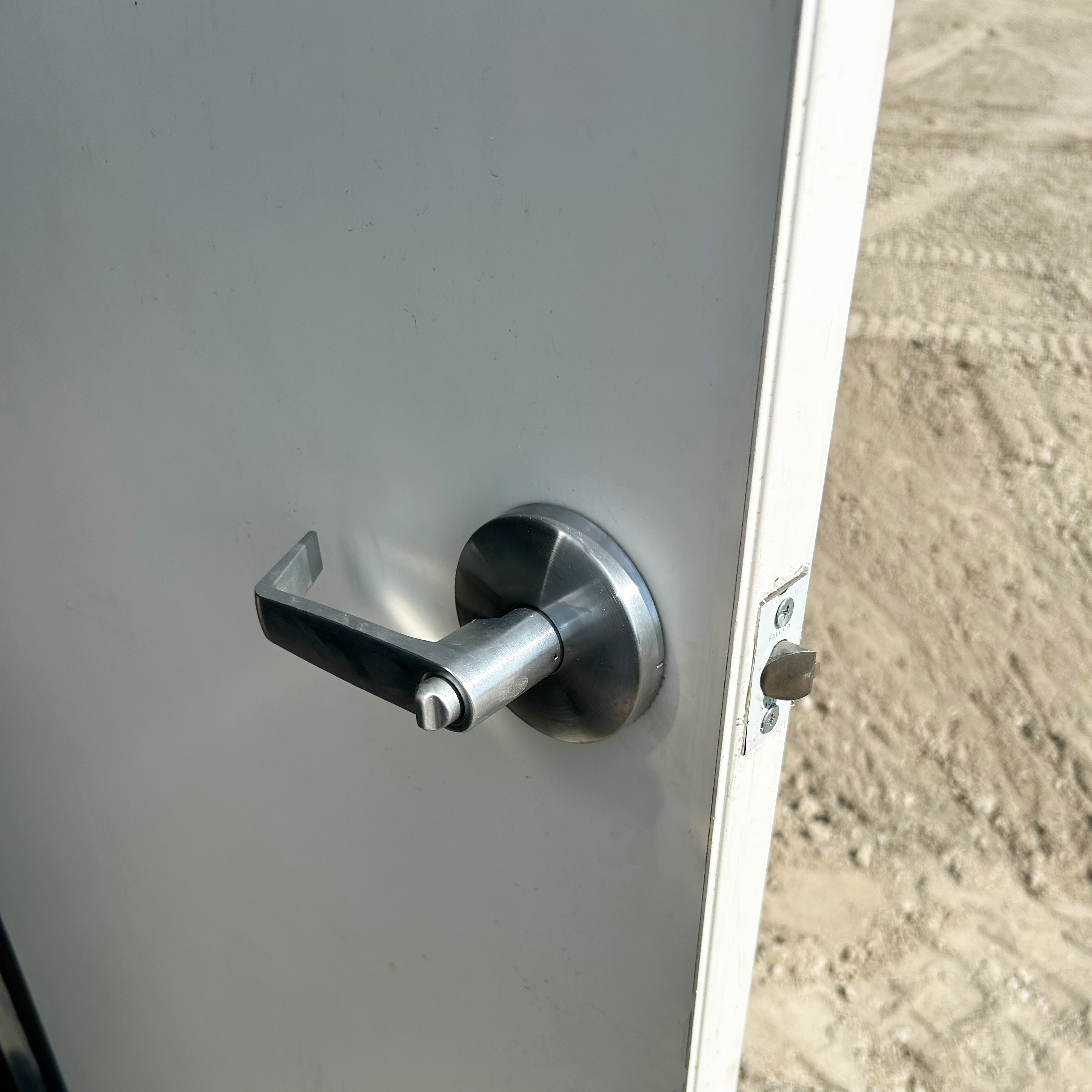 Close-up of door handle installed on the fiberglass man door slab, showing proper alignment and fit with pre-drilled holes and included hardware for secure container access.