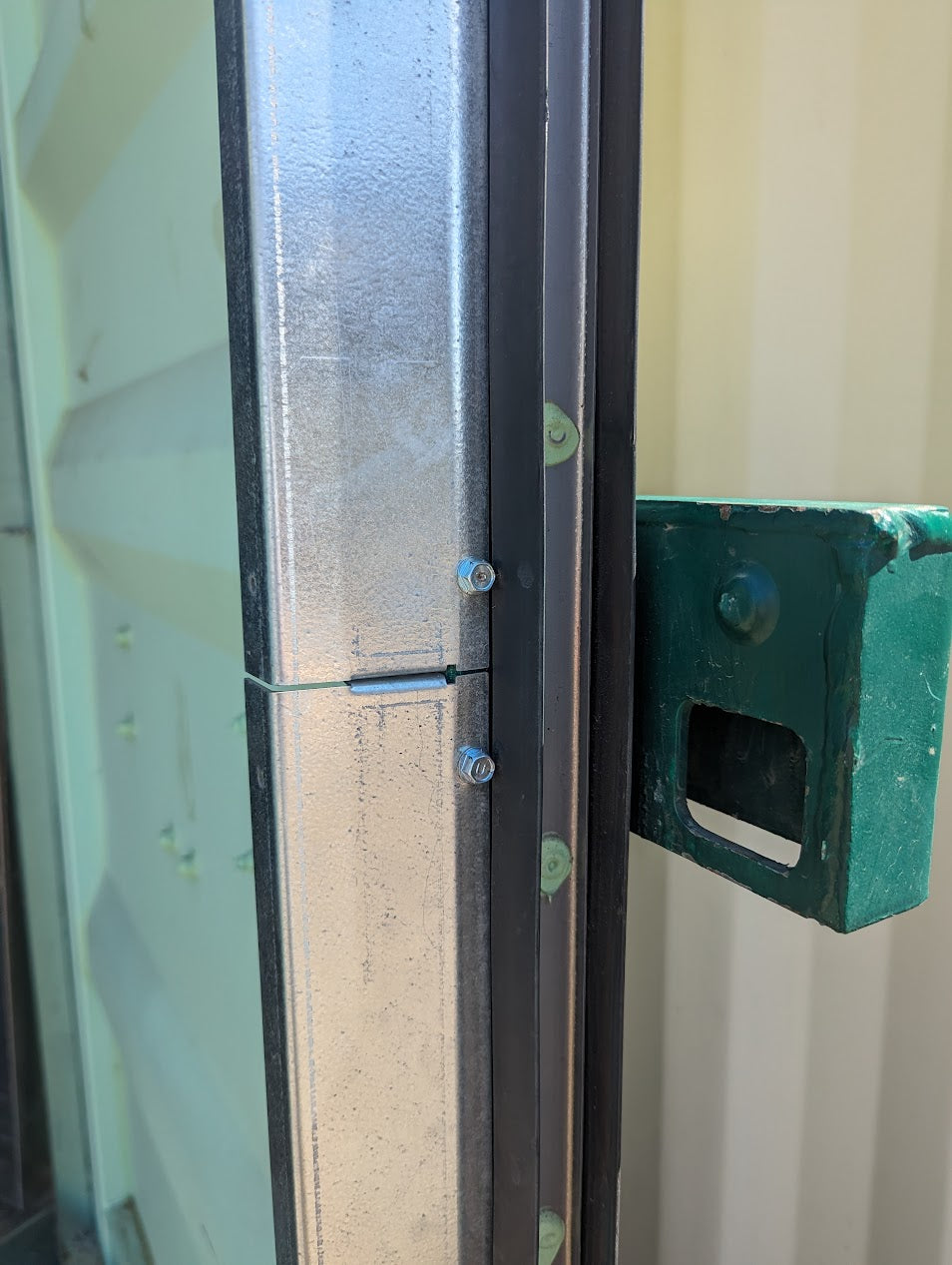 Close-up of galvanized steel flashing kit installed on a shipping container door, showing clean seam alignment and included self-tapping screws for secure attachment.