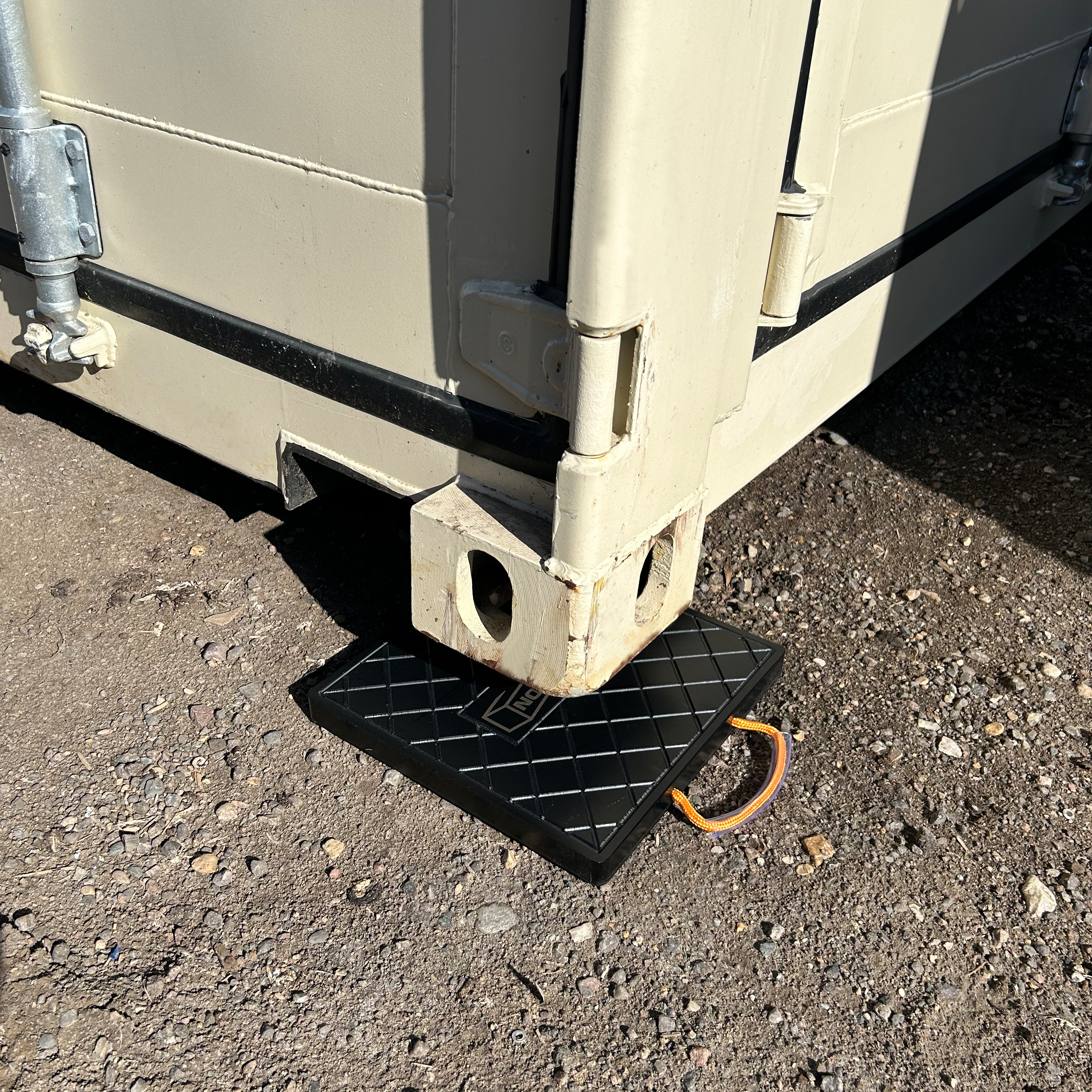 Container corner pad raising container 1.5 inches to prevent sinking into soil