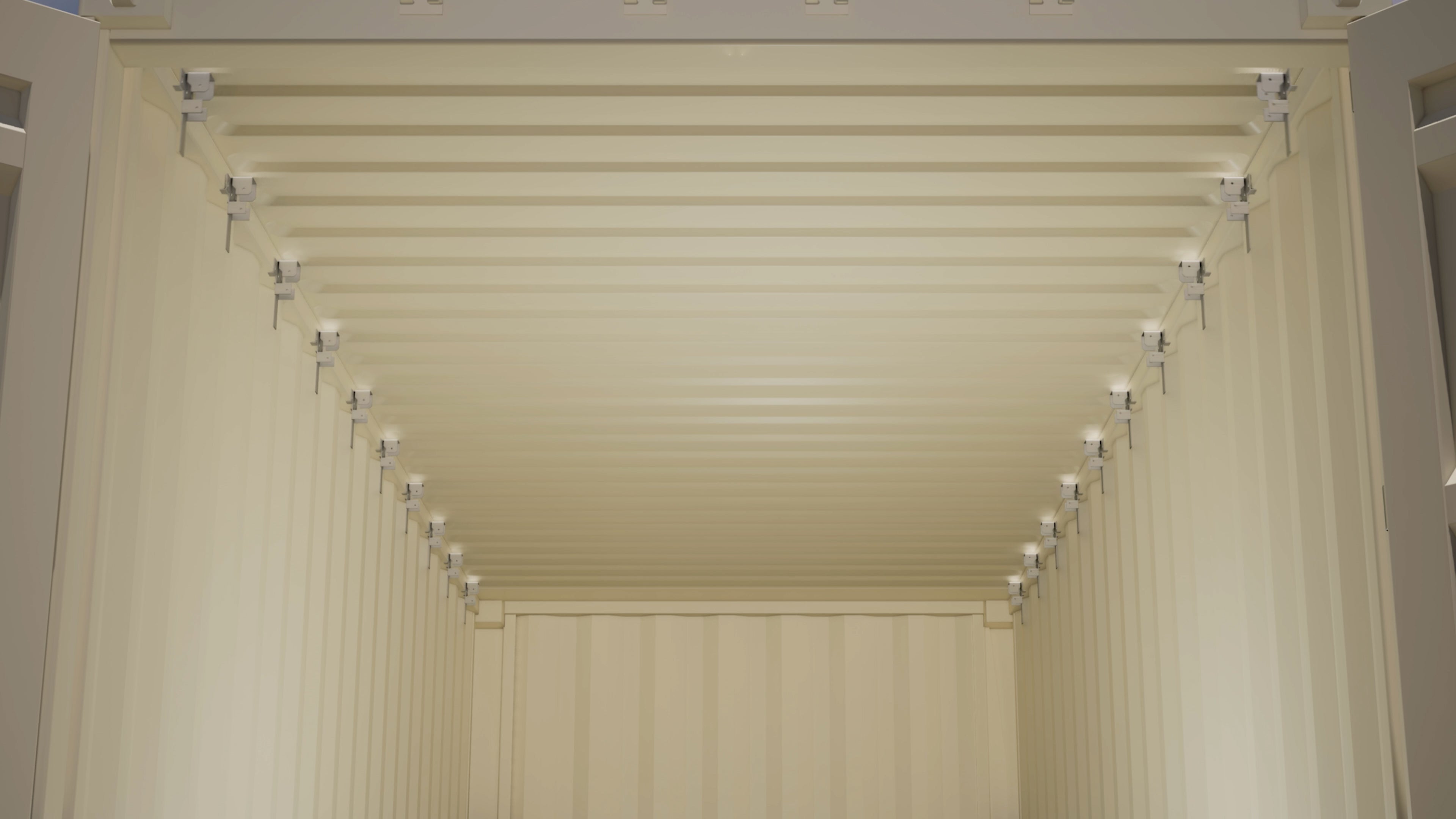 Interior view of a shipping container with aluminum wood stud brackets evenly installed along the top tubing on both walls for framing installation
