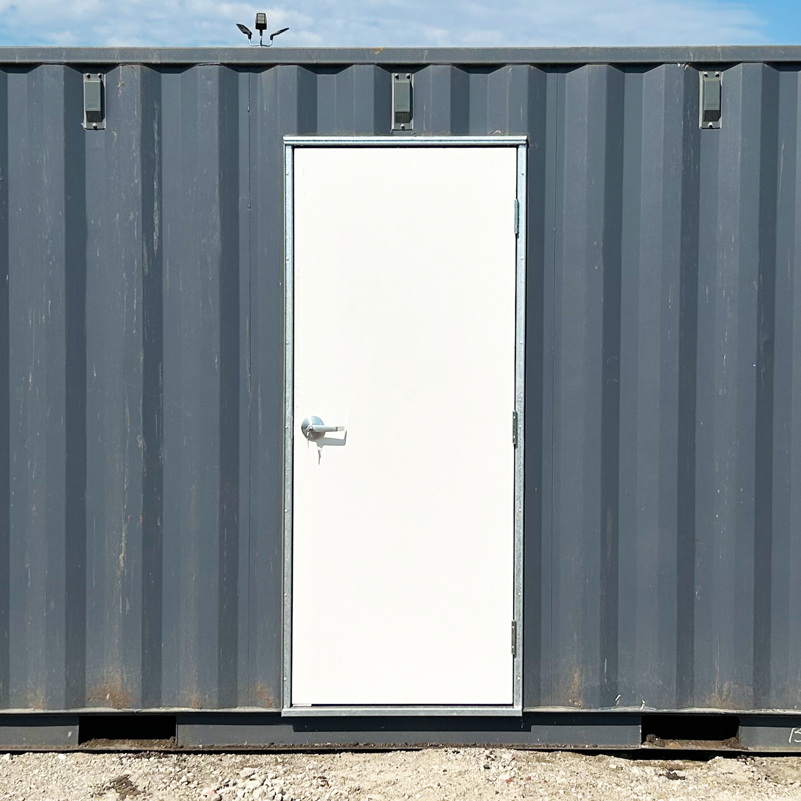 Installed commercial man door on shipping container, providing secure and weatherproof access with included hardware