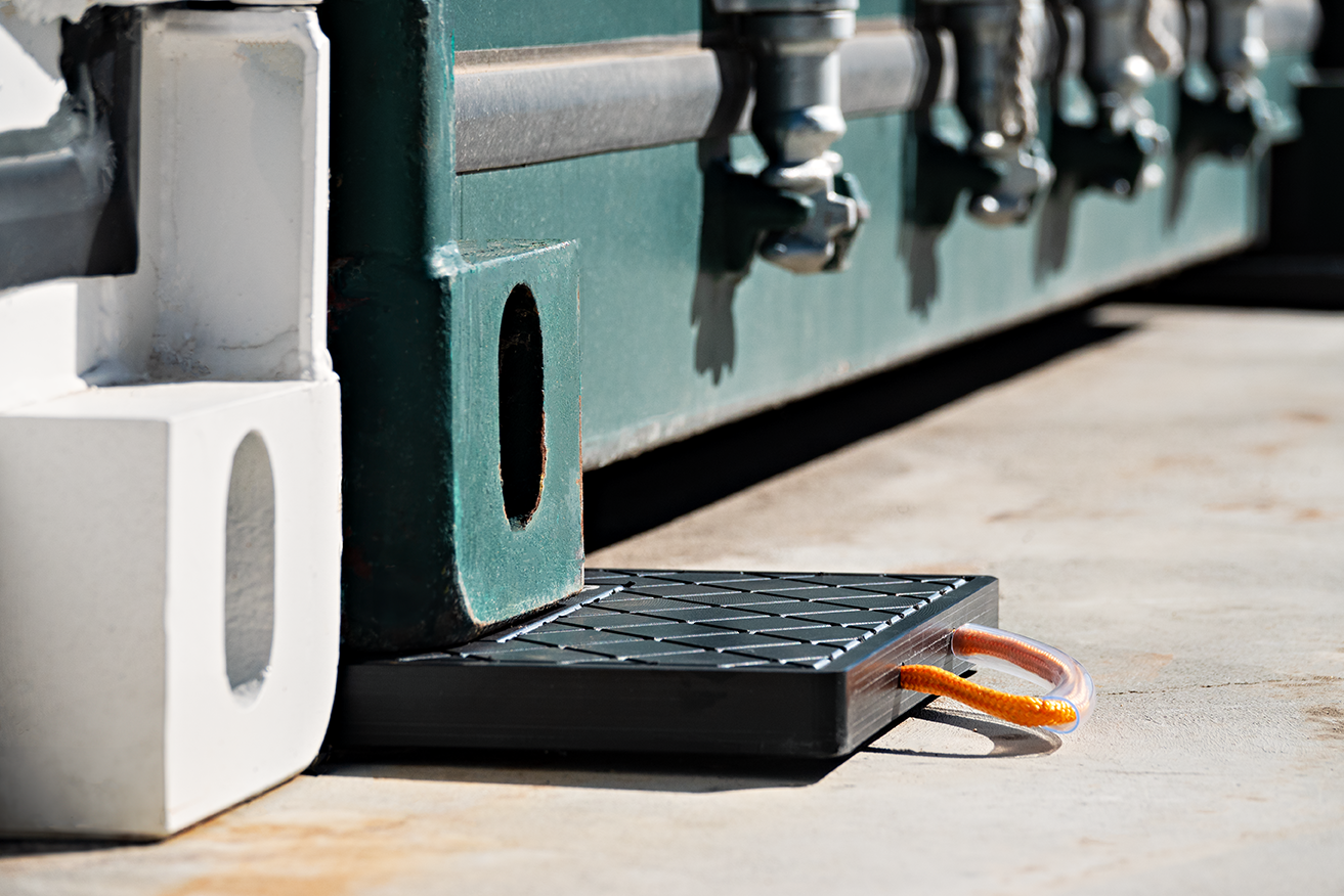 Container corner pads installed under shipping container corners on paved surface